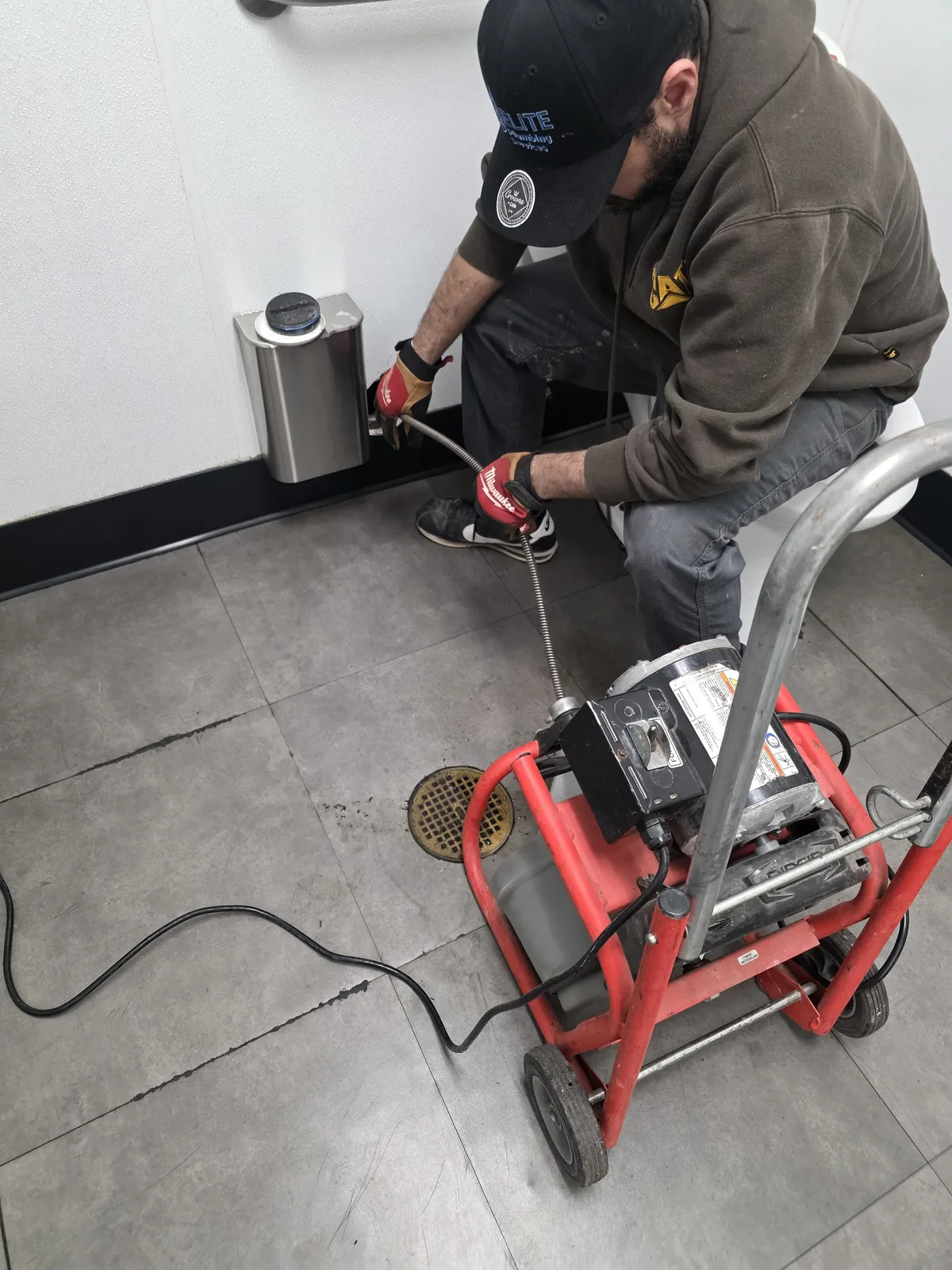Elite Plumbing technician clearing a commercial floor drain